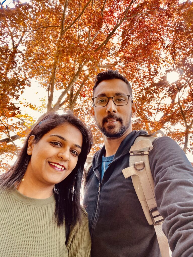 A girl and a boy under the a tree with red autumn colors