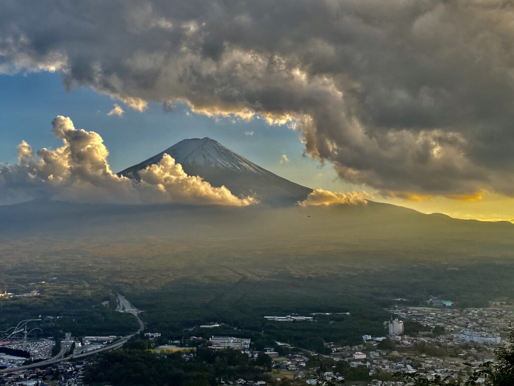 Mount Fuji surrounded by clouds and shimmering during sunset