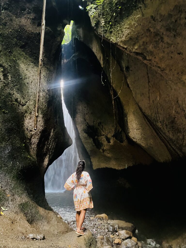 Girl standing near the cave waterfall